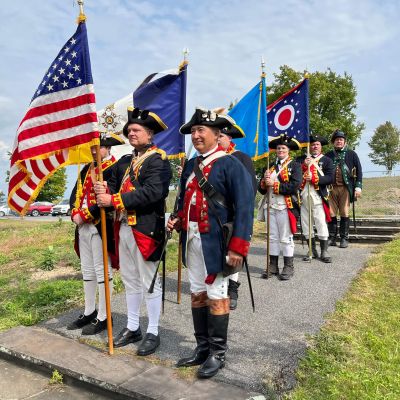 Revolutionary War reenactors marching with flags and swords