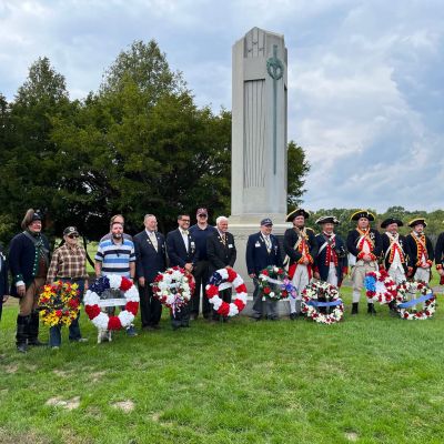 People standing near a monument with celebratory wreaths