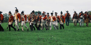 Revolutionary War reenactors marching through a field