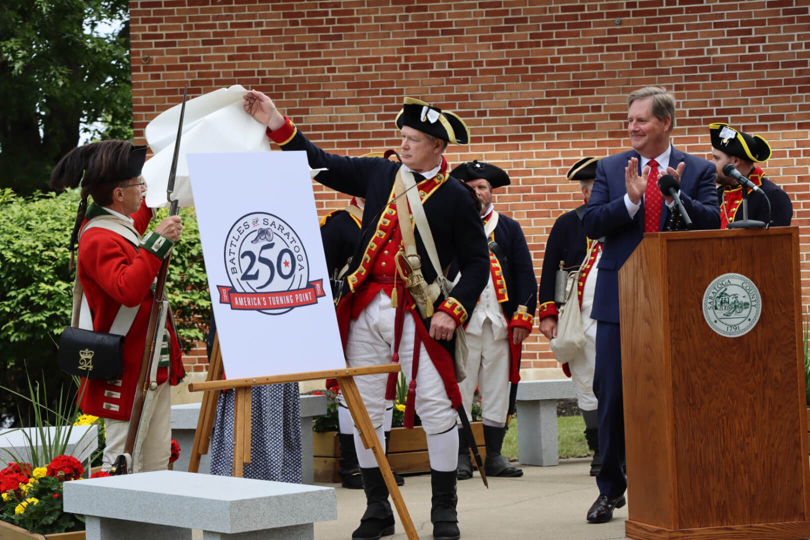 Revolutionary War reenactors unveiling the Battles of Saratoga 250 brand at a press conference