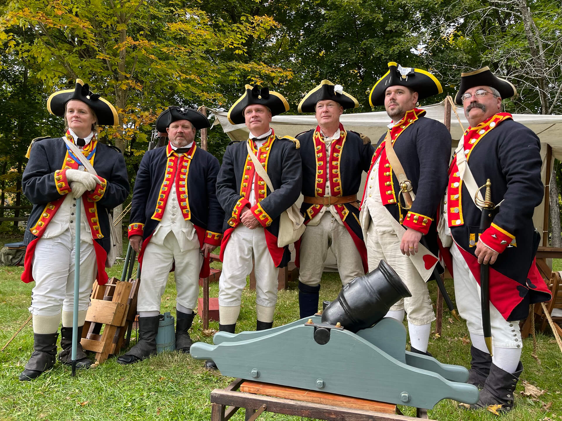 Revolutionary War reenactors near a tent with a small cannon